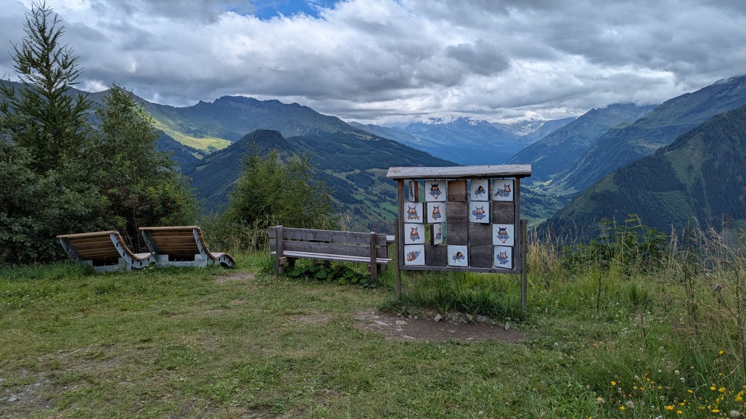 Holzbank an einem Aussichtspunkt mit Bergpanorama und einer Schautafel mit Eulen